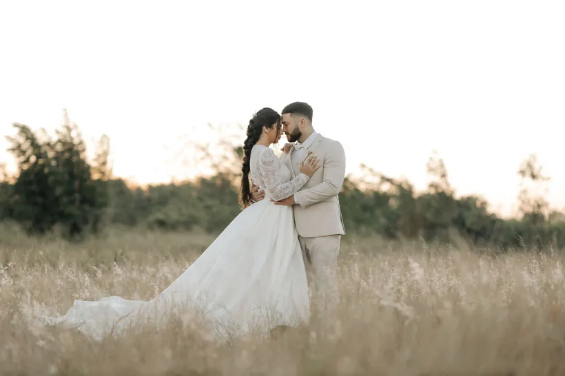 Casal abraçado em um campo ao pôr do sol